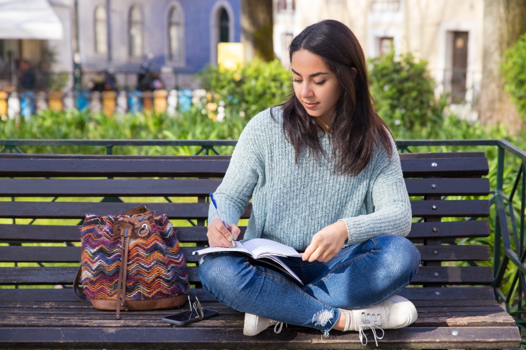 Young woman studying outdoors on a park bench